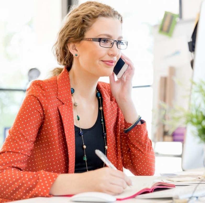 young-woman-holding-mobile-phone-in-office-PE9ARDR-768x640